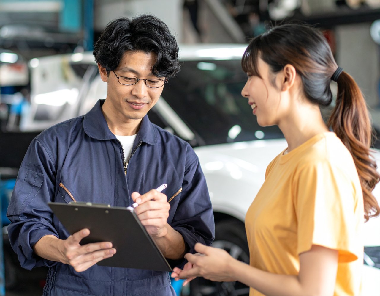 Firefly_データをもとに、女性のお客様へ説明をする整備士