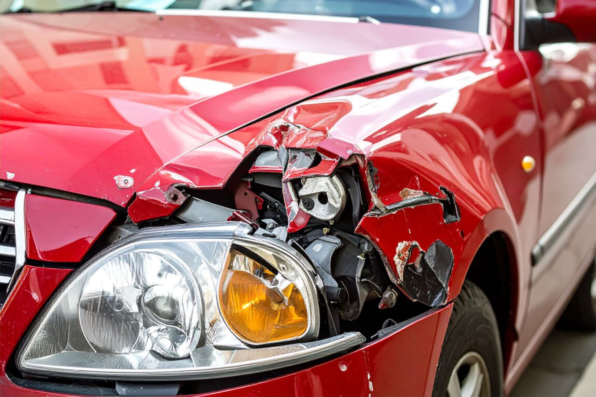 前方が激しく損傷した赤い自動車の事故車両