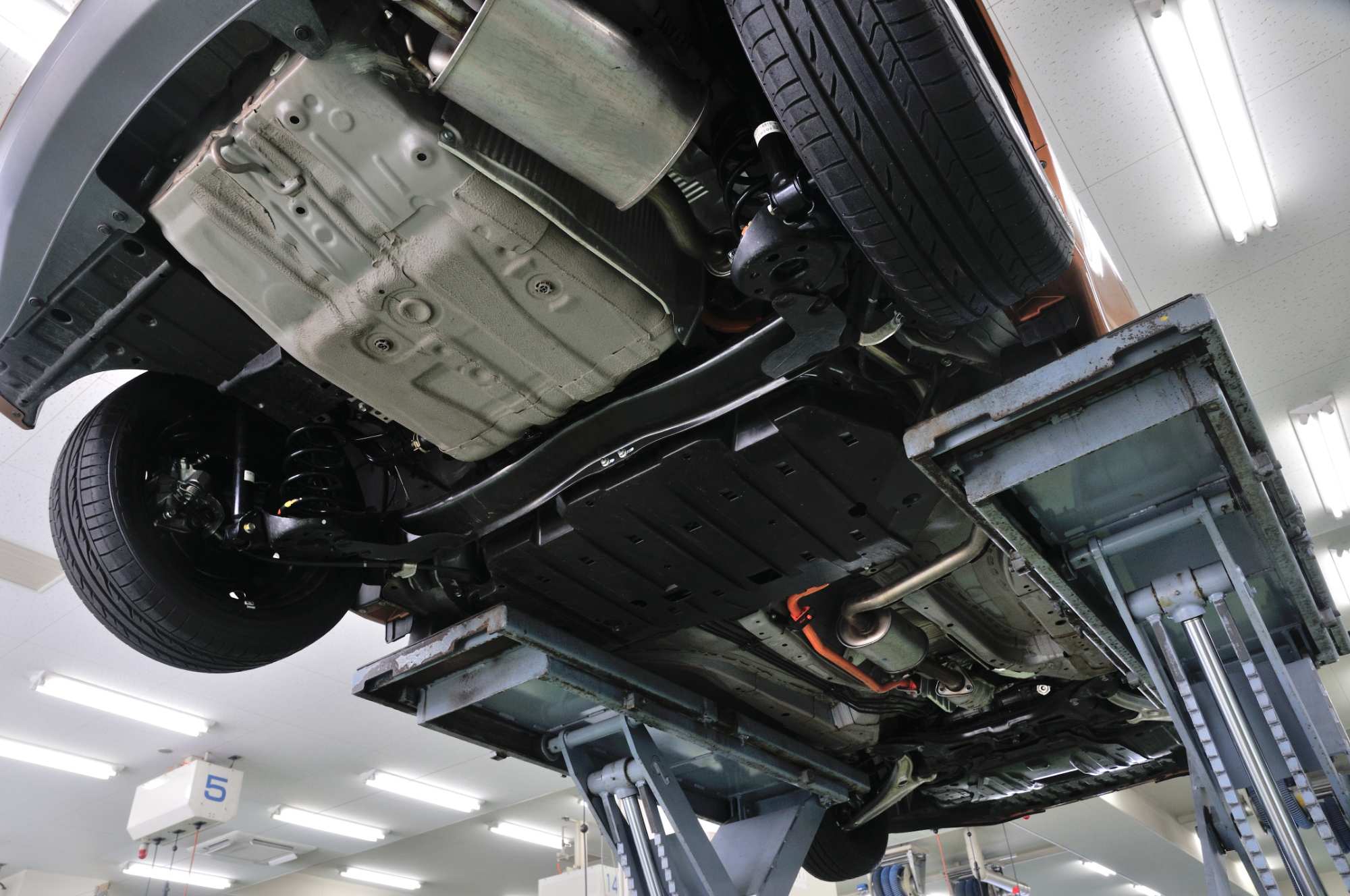 整備用リフトで持ち上げられた車両の底面とサスペンション部品